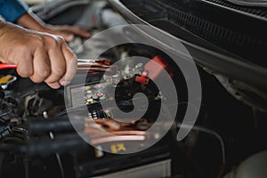 Close up of hand Charging car battery with electricity trough jumper cables