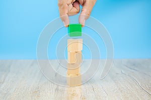 Close-up hand choose a cube shape wooden block toy stacked without graphics for Business design concept