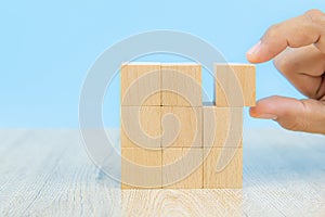 Close-up hand choose a cube shape wooden block toy stacked without graphics