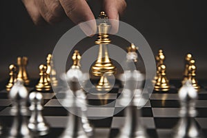 Close up hand choose gold chess to challenge with silve chess team on chess board