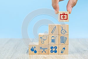 Close-up hand choose Health care and medical symbol icons on wooden toy blocks.