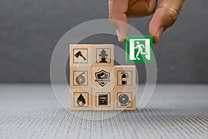 Close-up hand choose a wooden toy blocks with fire exit icon for fire safety protection