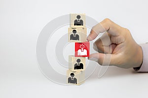 Close up hand choosing people icons with a light bulb on cube wooden toy blocks concepts of idea human resources for business