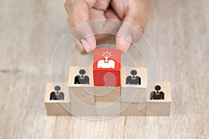 Close up hand choosing people icons with a light bulb on cube wooden toy blocks stack in pyramid shape