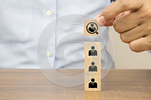 Close up hand choosing people in a magnifying glass icons on cube wooden toy blocks