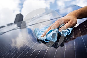 Close-up of a hand cleaning a solar panel with a cloth