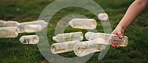 Close up hand collects plastic bottle in a park. A volunteer cleaning garbage.