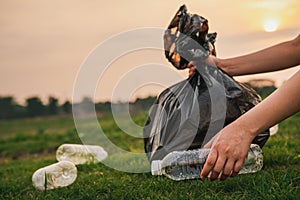 Close up hand collects plastic bottle in a park. A volunteer cleaning garbage.