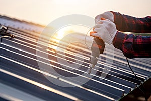 Close up hand of construction worker safety wear using electric drill tools install on new roof metal sheet, Roof construction