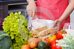 Close up of hand cooking and whisking eggs in a bowl in kitchen