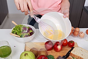 Close up of hand cooking and whisking eggs in a bowl in kitchen