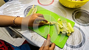 Close up hand cutting out the baby corn into several slice for cooking ingredients for making vegetable soup