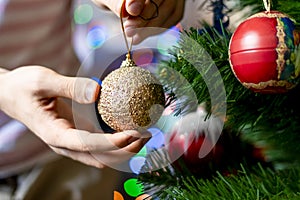 close up hand decorating the chrismas tree with beautiful red ball toy f