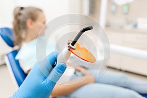 Close-up hand of dentist in the glove holds Dental polymerization lamp in dentist hand, with UV light and lase. The