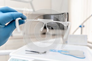 Close-up hand of dentist in the glove holds dental protective mask. Office where dentist conducts inspection and