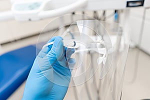 Close-up hand of dentist in the glove holds dental protective mask. Office where dentist conducts inspection and