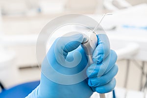 Close-up hand of dentist in the glove holds Gun dental water and air. . Office where dentist conducts inspection and