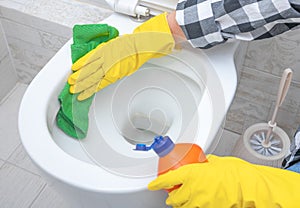 Close up hand with detergent cleaning toilet. Cleaning service. croped hands wearing yellow protect glove using liquid cleaning