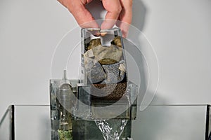 Close up of a hand disassembling a fish tank waterfall filter to clean it.