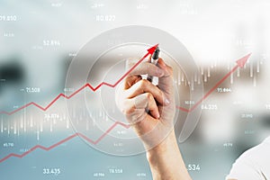 Close up of hand drawing growing red business chart arrow on blurry office interior background. Finance, profit and increase