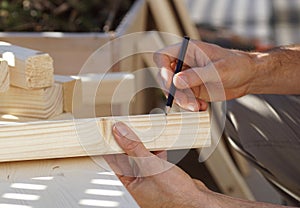 Close up of a hand drawing a line on a wooden beam