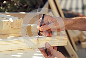 Close up of a hand drawing a line on a wooden beam