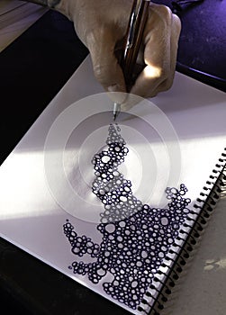 Close up of a hand drawing a pattern of scribbled bubbles on a blank scrapbook