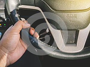 Close up hand driver control of car steering wheel