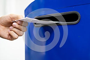 Close up hand drop letter and documents in the blue postbox in post office mail f