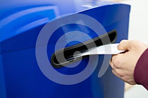 Close up hand drop letter and documents in the blue postbox in post office mail f