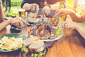 Close up hand, eating.Group Of People Dining Concept,With Chicken roasting,salad,French fries on wooden table