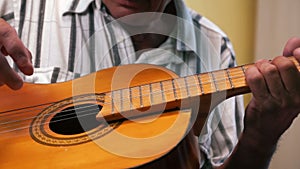 Close-up of the hand of an elderly man playing an old acoustic guitar, a pensioner recalls how to play a musical instrument. Selec