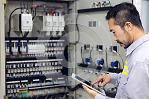 Close up hand of engineer or electrician man working check the electrical system with tablet at factory