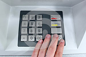 Close-up of hand entering pin code at ATM machine
