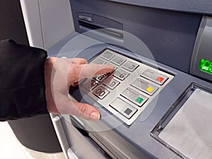 Close-up of hand entering PIN/pass code on ATM/bank machine keypad.