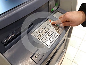 Close-up of hand entering PIN/pass code on ATM/bank machine keypad