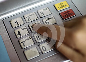 Close-up of hand entering PIN/pass code on ATM/bank machine keypad