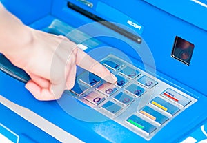 Close-up of hand entering PIN/pass code on blue ATM/bank machine keypad