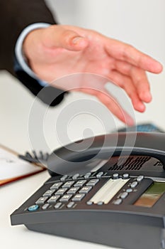 Close up of hand extending to office telephone photo