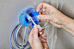 Close-up of a hand fasten the electrical box on wall.