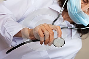 Close up hand female doctor in blue medical mask showing stethoscope for checkup auscultate heartbeat and breath patient. photo