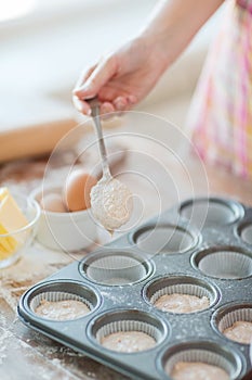 Close up of hand filling muffins molds with dough