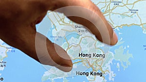 Close up hand gesture on touch screen zooming in Hong Kong city