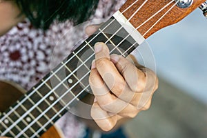 Close up hand girl play ukulele guitar at her home.