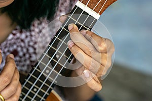 Close up hand girl play ukulele guitar at her home.