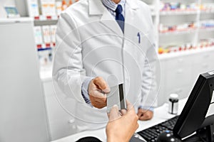 Close up of hand giving bank card to pharmacist