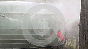 Close up of hand with gloves spraying compressed water to clean dirt of the boat surface outside. Fishing boat maintenance