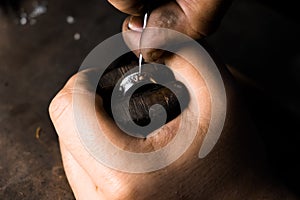 Close-up of hand of a goldsmith setting the diamond on the ring. Craft jewelery making with professional tools.