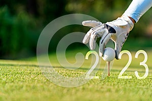 Close up hand Golfer woman putting golf ball for Happy New Year 2023 on the green golf for new healthy.