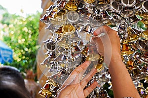 Close up Hand grab small golden and silver bells to hanging in Thai temple.